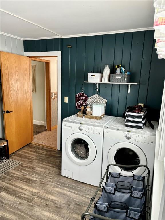 clothes washing area featuring crown molding, wood-type flooring, and washing machine and clothes dryer