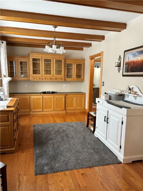 kitchen with sink, light hardwood / wood-style flooring, a notable chandelier, decorative light fixtures, and beamed ceiling