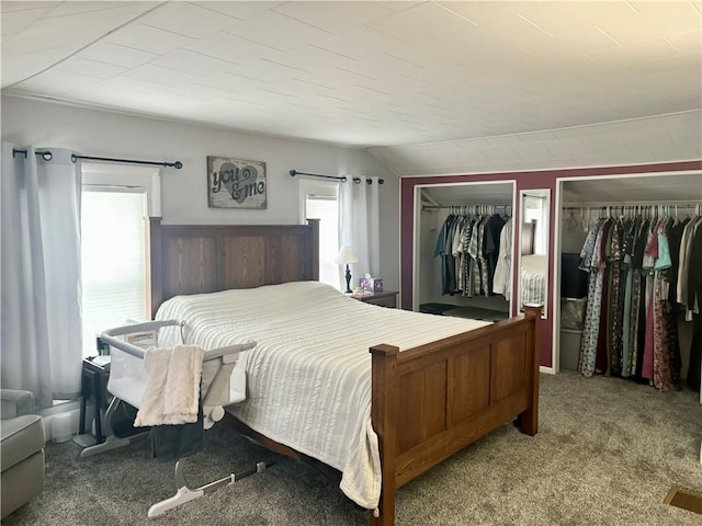 carpeted bedroom featuring vaulted ceiling and two closets