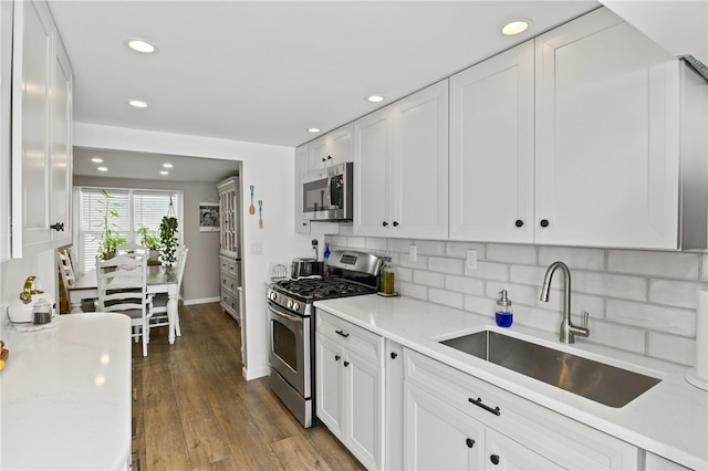 kitchen with sink, light hardwood / wood-style flooring, appliances with stainless steel finishes, light stone counters, and white cabinets