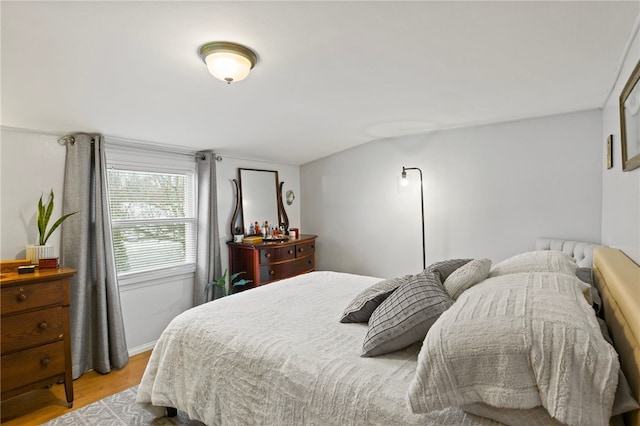 bedroom with vaulted ceiling and light wood-type flooring