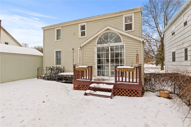 snow covered back of property featuring a wooden deck