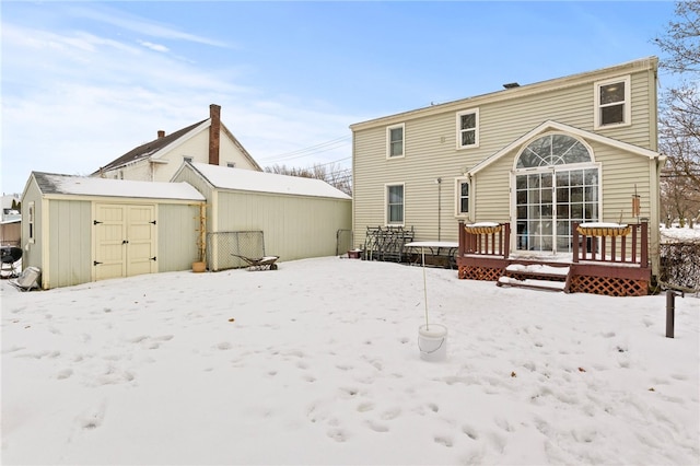 snow covered property featuring a wooden deck and a storage unit