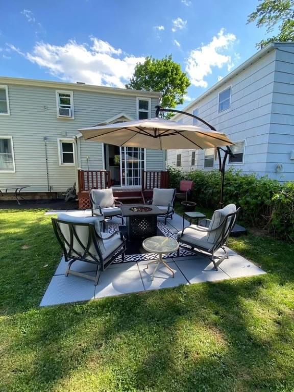 rear view of property with a patio, a lawn, and an outdoor fire pit