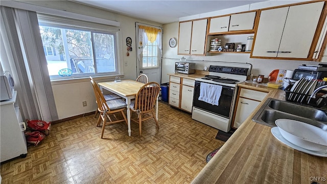 kitchen featuring sink, white electric range, light parquet floors, and white cabinets