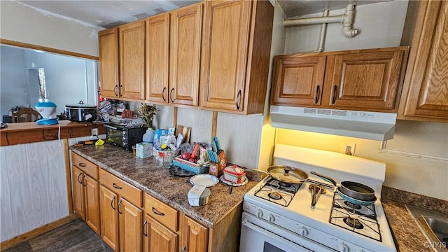 kitchen with white range with gas cooktop and dark stone countertops