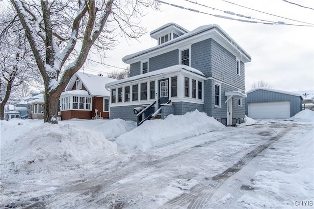 view of property featuring a garage, a sunroom, and an outbuilding