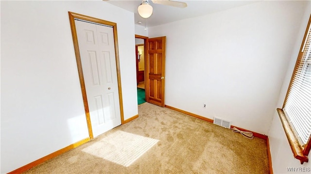 unfurnished bedroom featuring light carpet, a closet, and ceiling fan