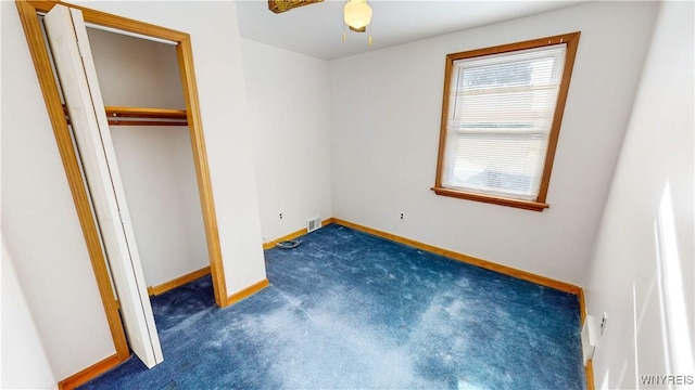 unfurnished bedroom with dark carpet and a closet