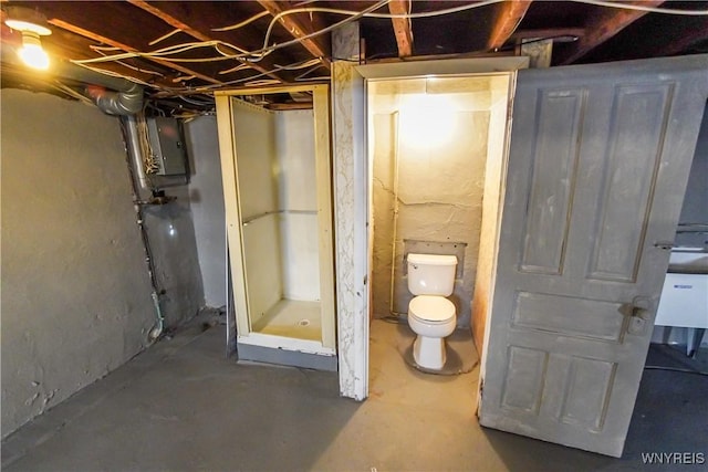 bathroom with concrete flooring, electric panel, and toilet