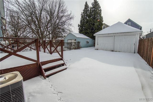 snowy yard featuring an outbuilding, a garage, and cooling unit