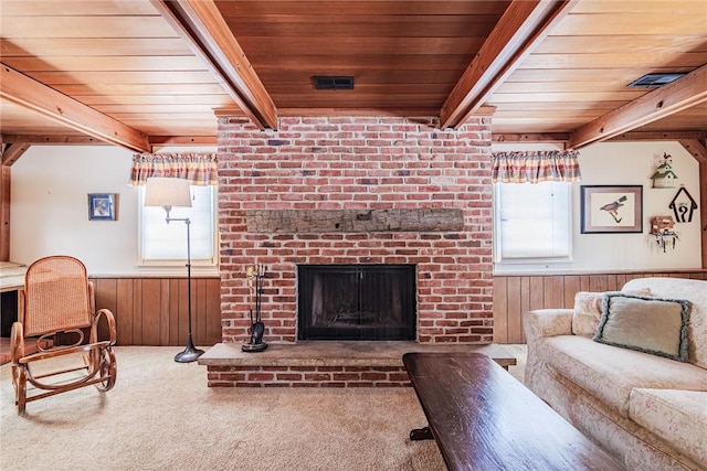 carpeted living room with a fireplace, wood ceiling, wooden walls, and beamed ceiling