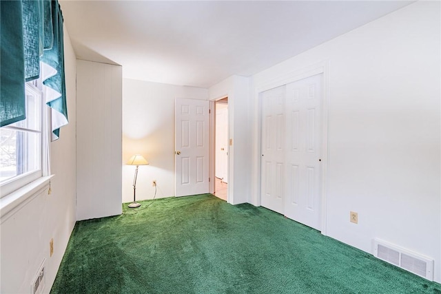 unfurnished bedroom with dark carpet and a closet