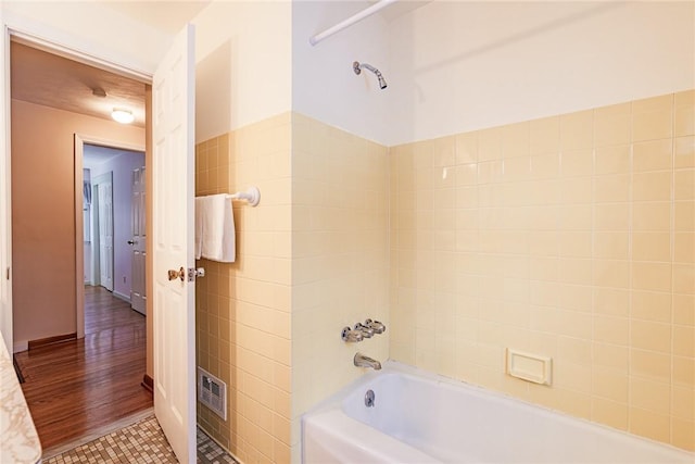 bathroom featuring tile walls, tile patterned floors, and tiled shower / bath