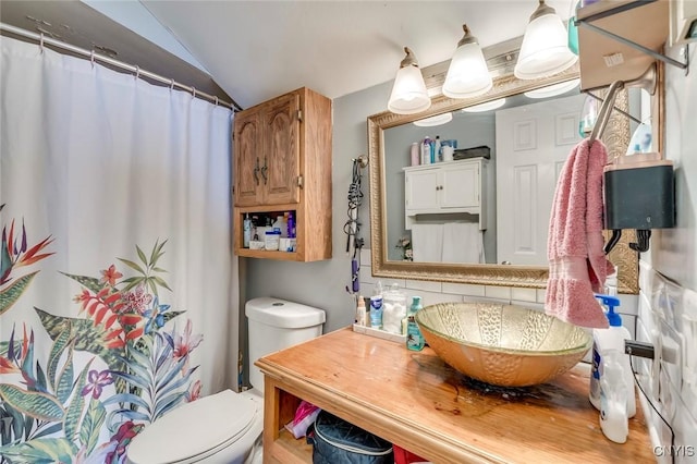 bathroom with sink, toilet, vaulted ceiling, and decorative backsplash