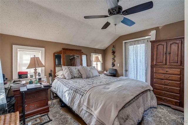 bedroom with ceiling fan, lofted ceiling, and a textured ceiling