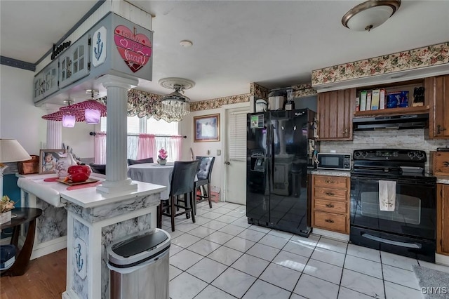 kitchen featuring decorative columns, tasteful backsplash, light tile patterned flooring, and black appliances