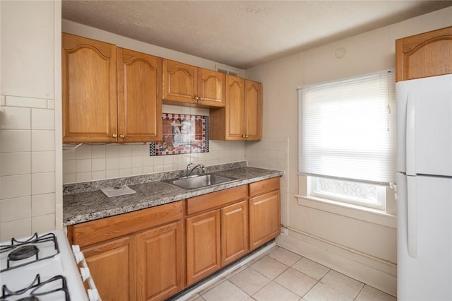 kitchen with backsplash, white appliances, sink, and light tile patterned floors