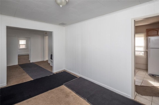 spare room featuring a baseboard heating unit, crown molding, and carpet floors