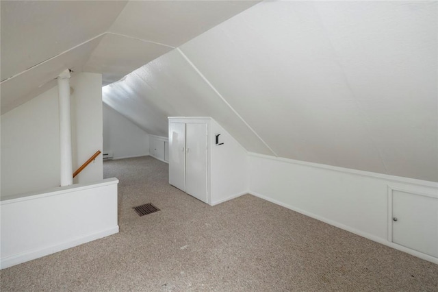 additional living space with vaulted ceiling, light carpet, and a baseboard heating unit