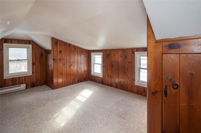 additional living space featuring carpet flooring, lofted ceiling, wooden walls, and a baseboard radiator