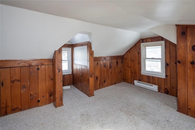 bonus room with baseboard heating, light colored carpet, plenty of natural light, and wooden walls