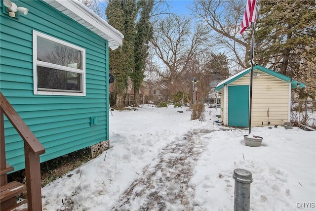 snowy yard featuring a shed