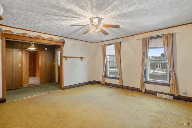 spare room with a healthy amount of sunlight, carpet flooring, ceiling fan, and ornamental molding