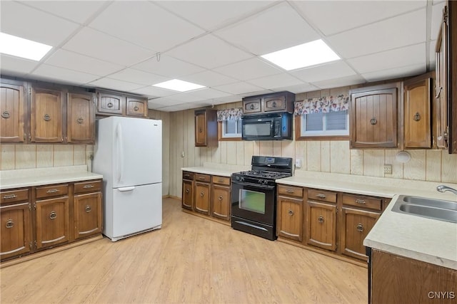 kitchen with sink, a paneled ceiling, light hardwood / wood-style floors, and black appliances