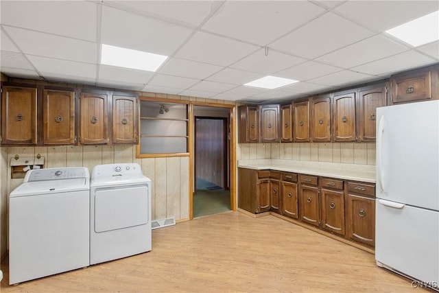 laundry area featuring wooden walls, light hardwood / wood-style floors, and independent washer and dryer