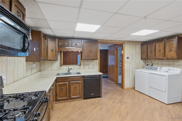 kitchen with washer and dryer, sink, black appliances, a drop ceiling, and light wood-type flooring