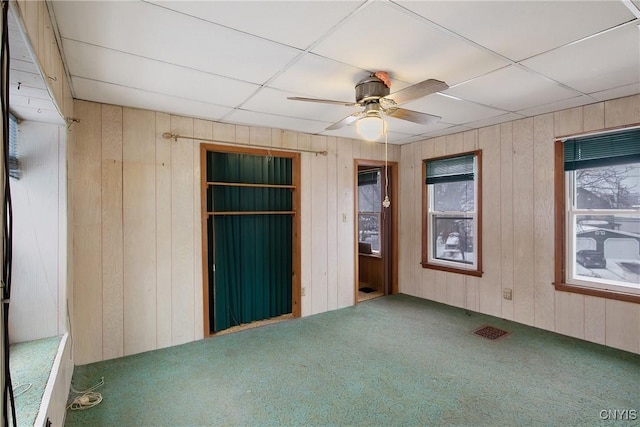 unfurnished bedroom featuring ceiling fan, wooden walls, and carpet flooring