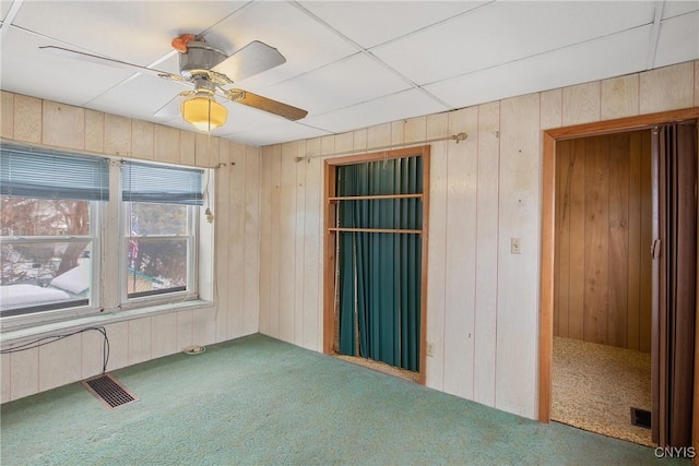 carpeted spare room featuring ceiling fan and wooden walls