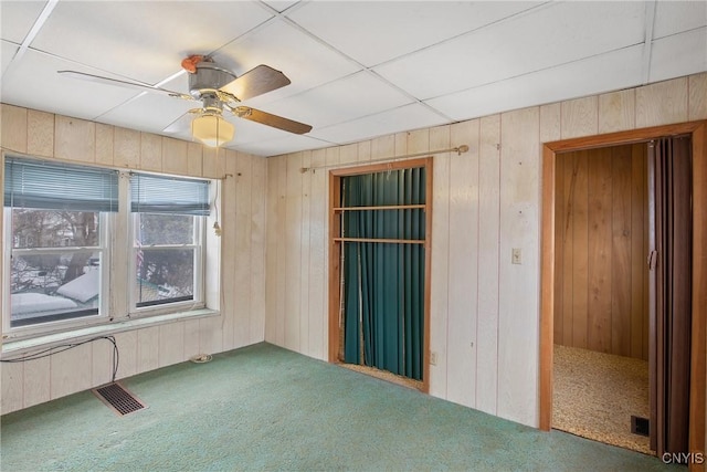 carpeted spare room featuring ceiling fan and wooden walls