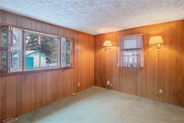 carpeted empty room featuring wooden walls