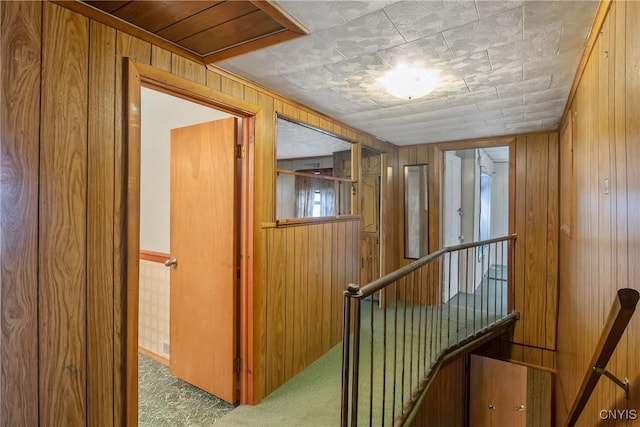 hallway featuring carpet and wood walls