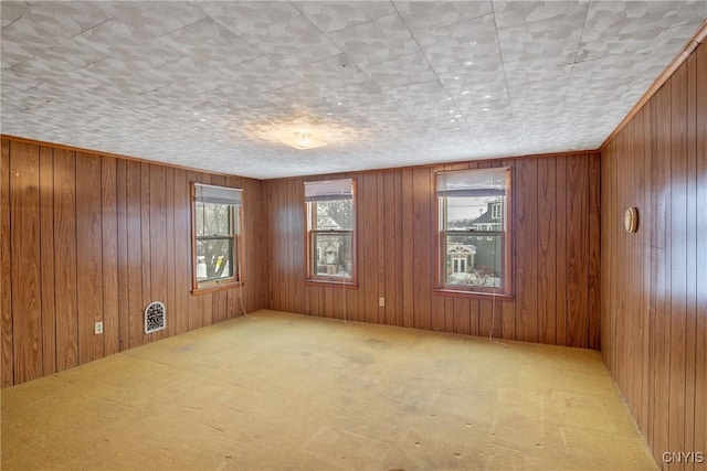 carpeted spare room with wooden walls