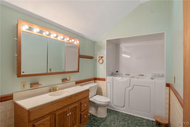 bathroom featuring lofted ceiling, tile walls, vanity, a bath, and toilet