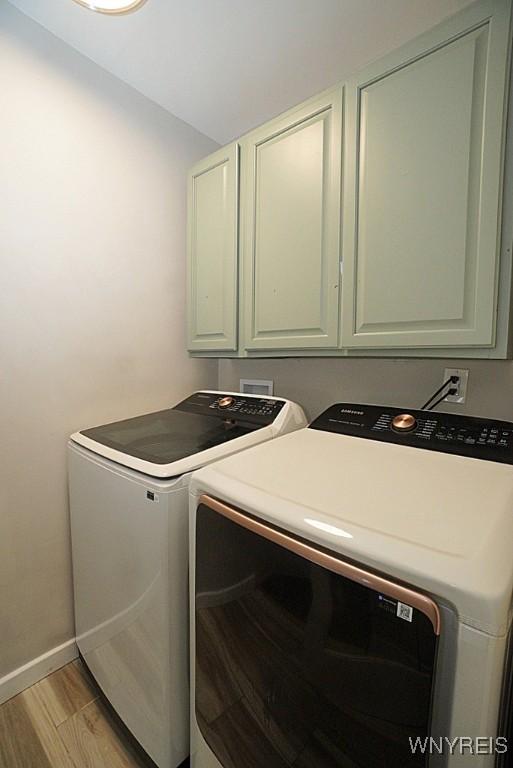 laundry room featuring cabinets, light wood-type flooring, and washer and clothes dryer