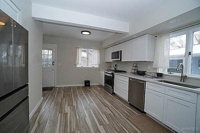 kitchen featuring sink, white cabinetry, appliances with stainless steel finishes, a healthy amount of sunlight, and light hardwood / wood-style floors