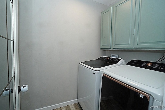 washroom featuring hardwood / wood-style flooring, cabinets, and washer and dryer