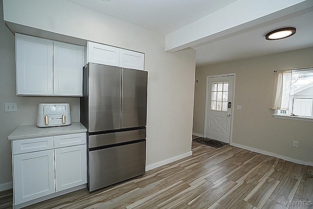 kitchen featuring stainless steel refrigerator, white cabinets, and light wood-type flooring