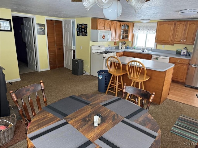 dining area featuring light carpet, sink, and a textured ceiling