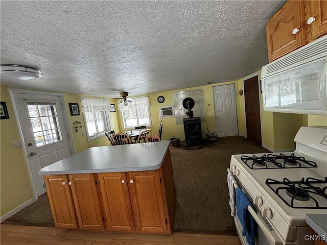 kitchen featuring a wood stove, a center island, white appliances, a textured ceiling, and a wall unit AC