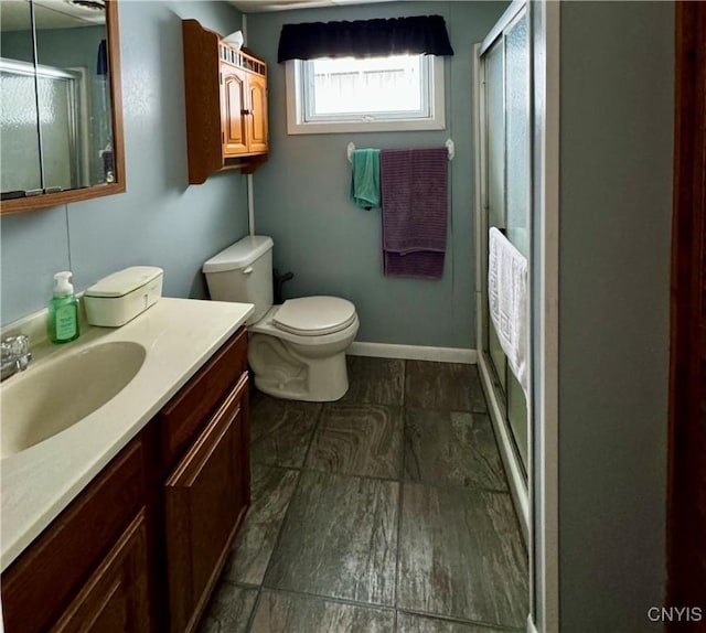 bathroom featuring vanity, an enclosed shower, and toilet