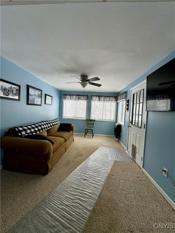 living room featuring heating unit, ceiling fan, and light carpet