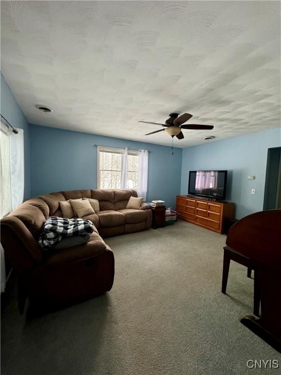 living room with a textured ceiling, carpet floors, and ceiling fan