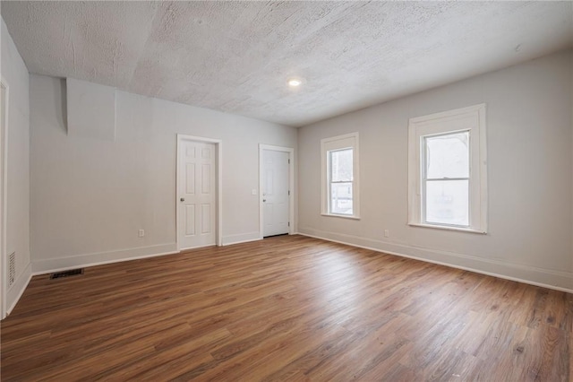 spare room with dark hardwood / wood-style floors and a textured ceiling