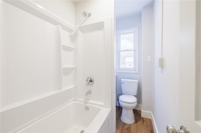 bathroom with hardwood / wood-style flooring, shower / washtub combination, and toilet