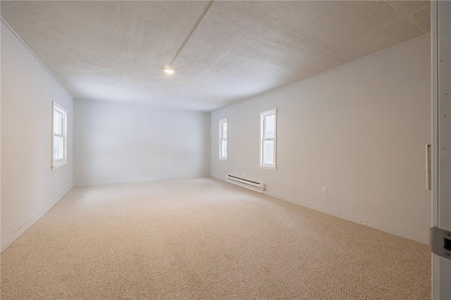 spare room featuring light carpet, a baseboard heating unit, and a textured ceiling